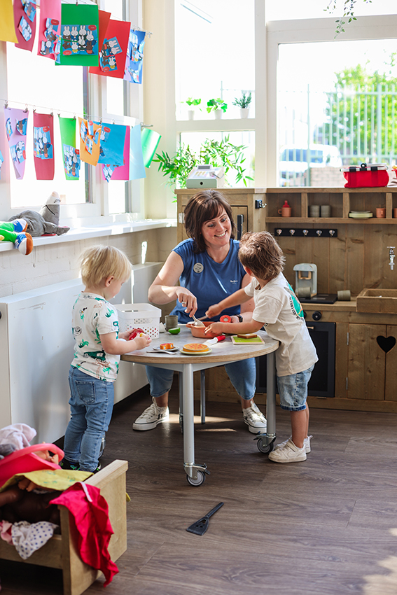 Liefdevolle medewerker die aan het spelen is met de kinderen van SKH stichting kinderopvang huizen