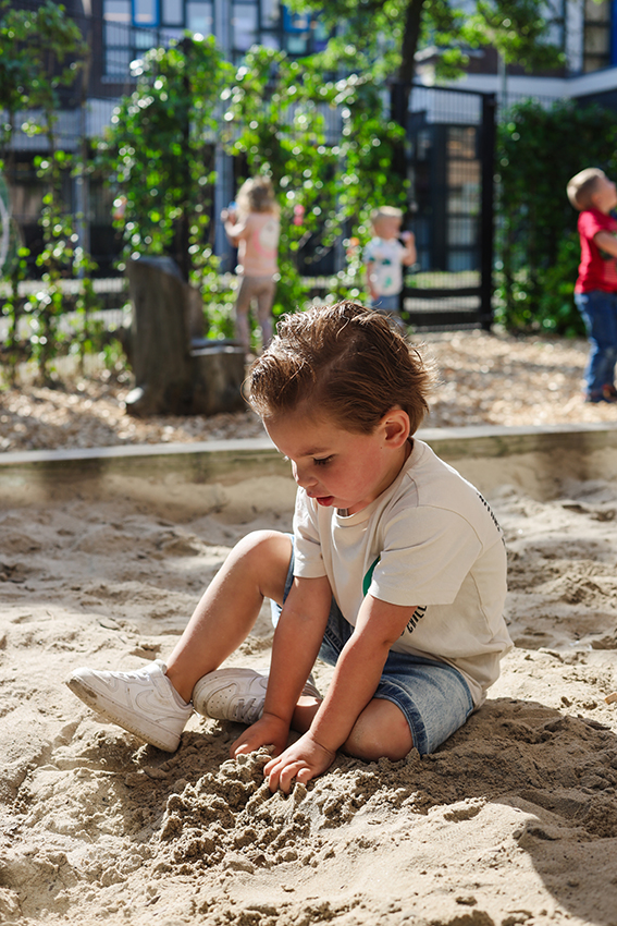 Een kindje van kinderopvang huizen die aan het spelen is in de tuin