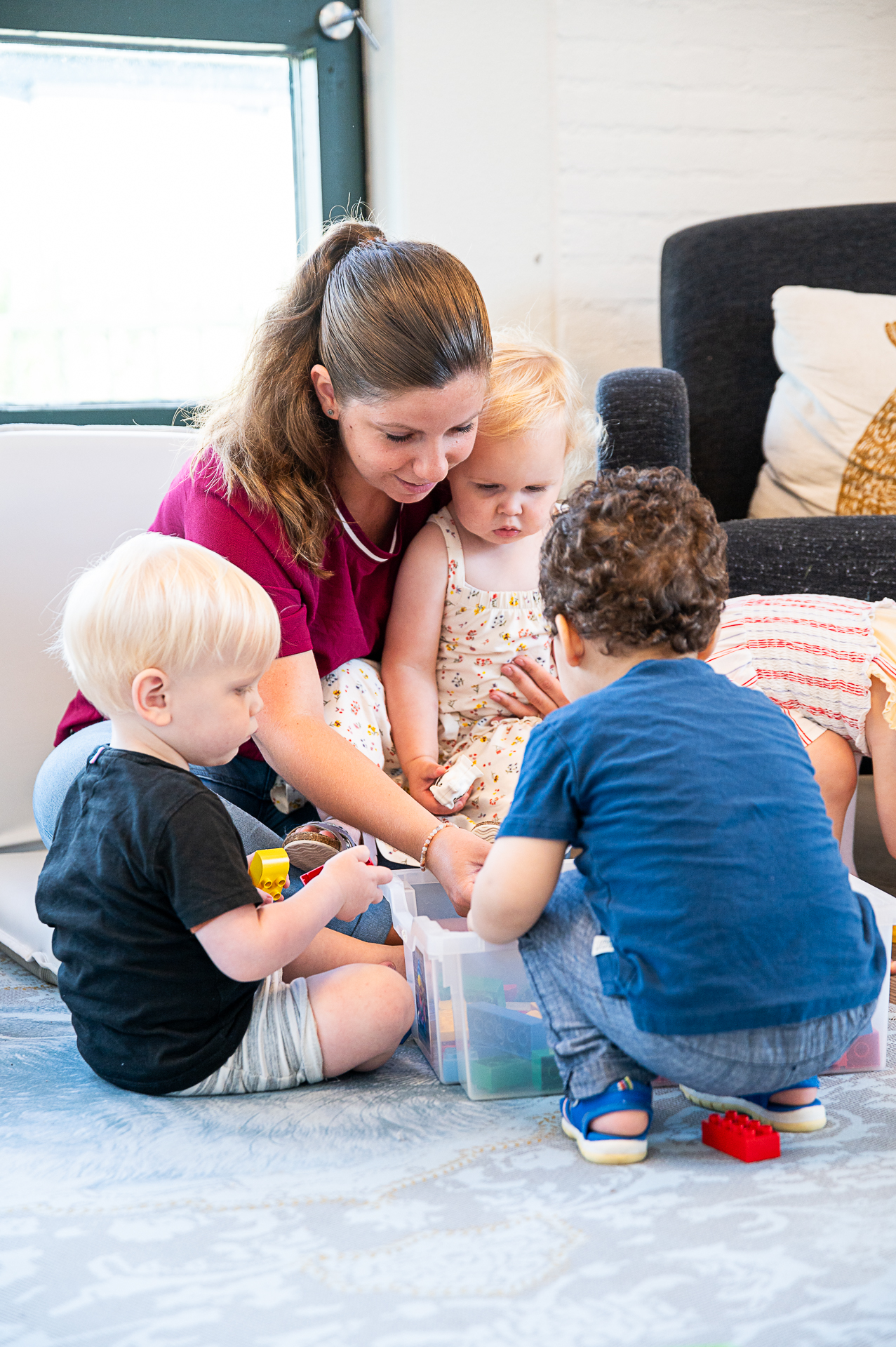 Een liefdevolle medewerker die met de peuters aan het spelen is op SKH kinderopvang huizen