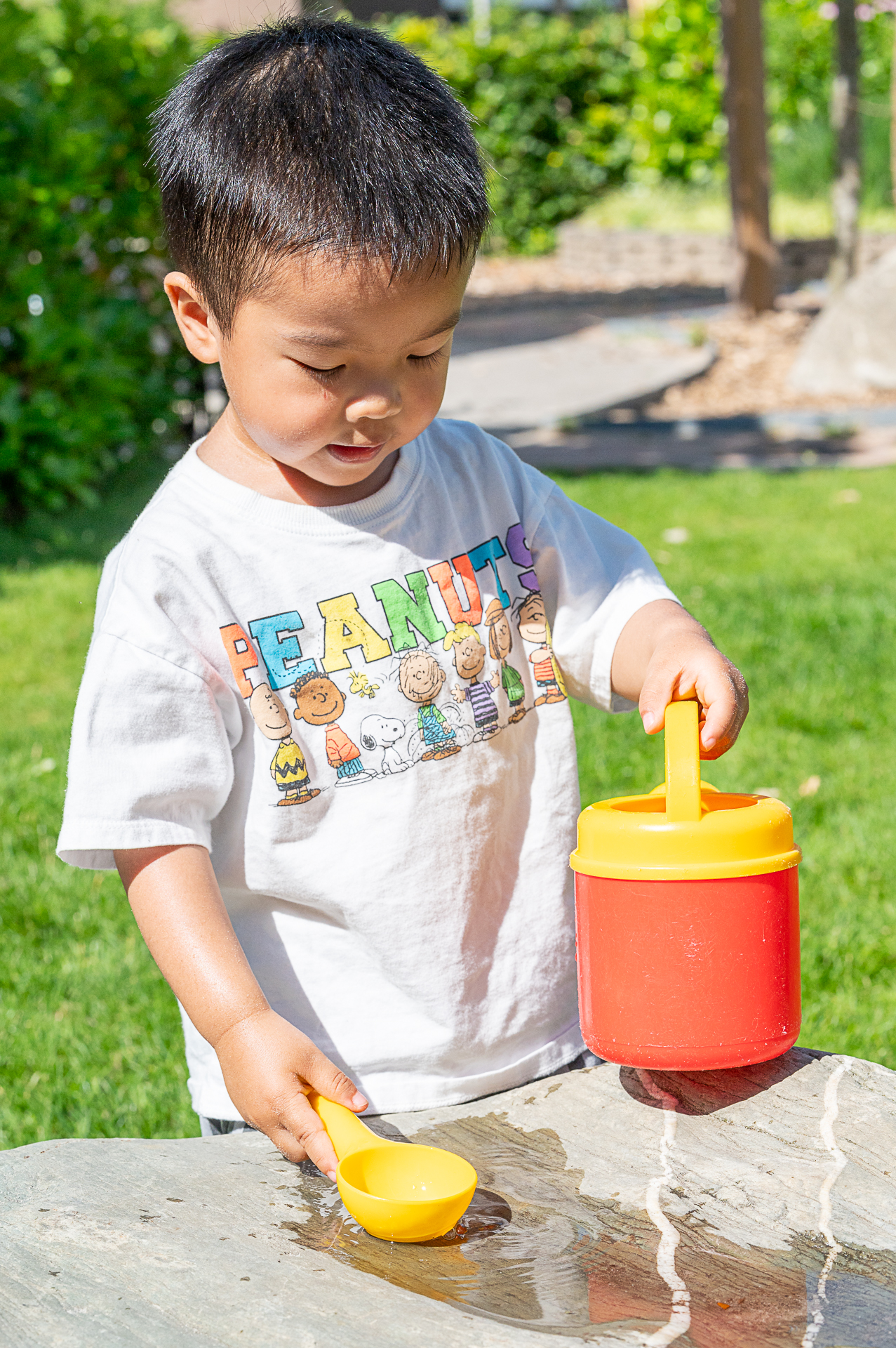 Jongetje aan het spelen met water bij het kinderdagverblijf van SKH kinderopvang huizen