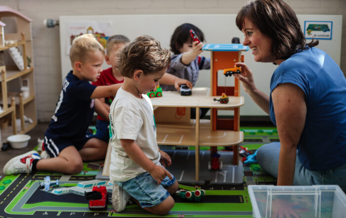 Een liefdevolle medewerker die aan het spelen in met de kinderen bij stichting kinderopvang huizen SKH